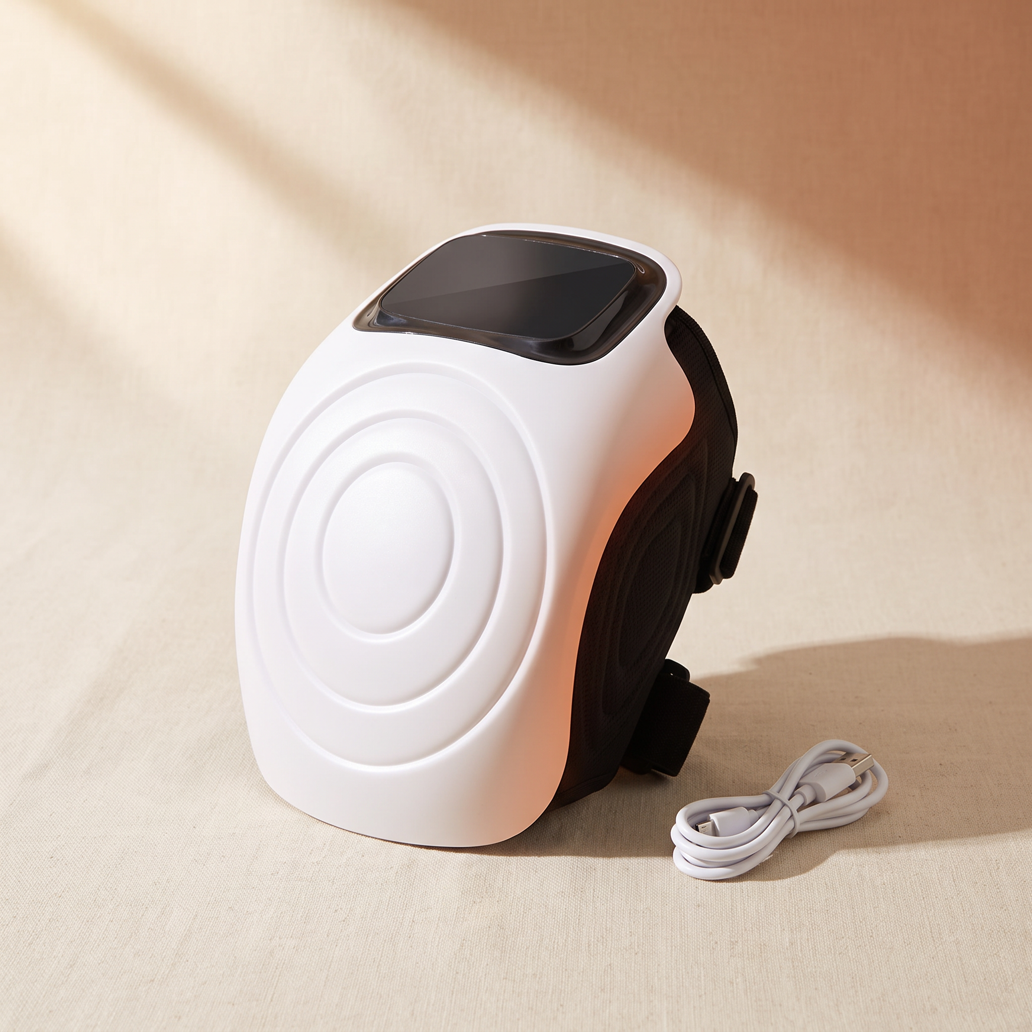 White heated knee massager with adjustable straps on a cream studio backdrop